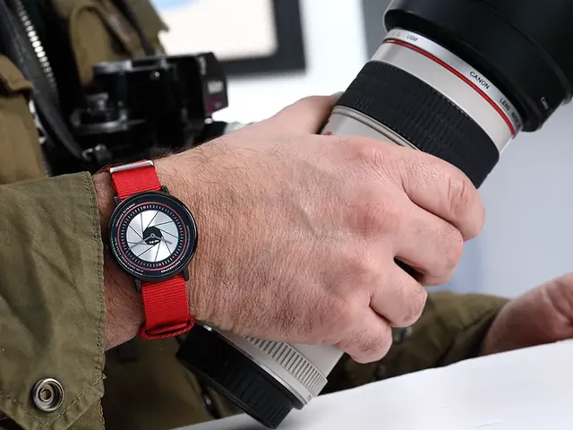 Montre au bracelet rouge portée au poignet d’un photographe tenant son appareil